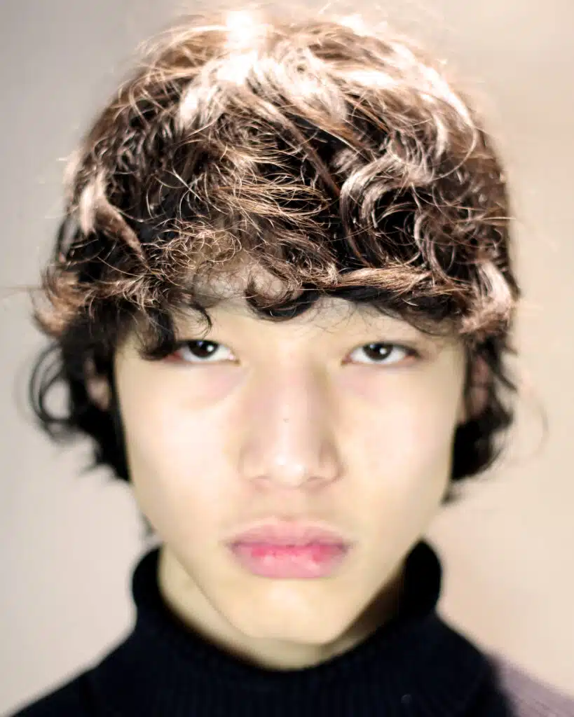 A young man with brown hair and pink lips.