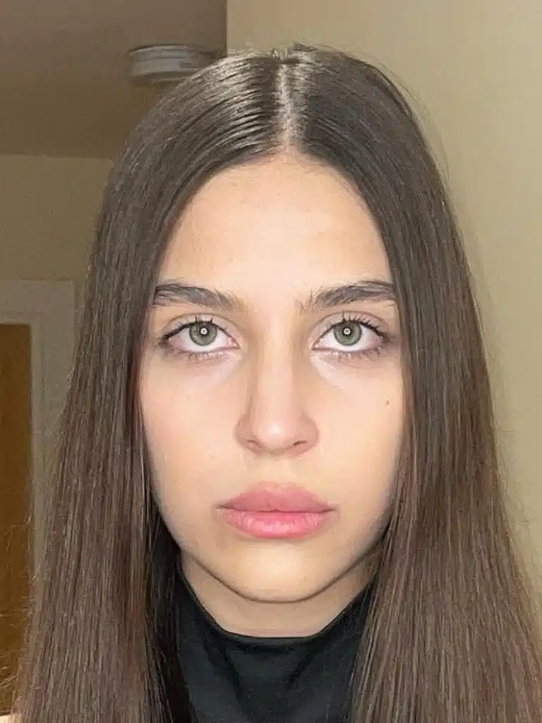 A woman with long hair and pink lipstick.