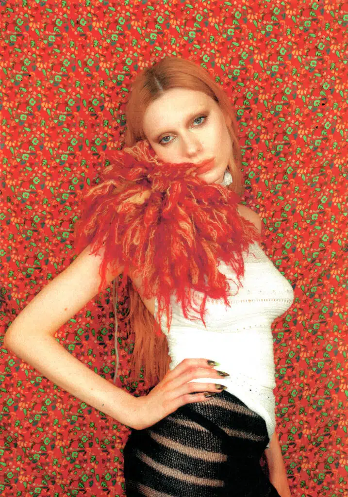 A woman with long red hair and a white top.