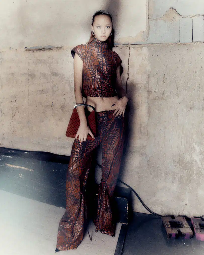 A woman in brown outfit standing next to wall.