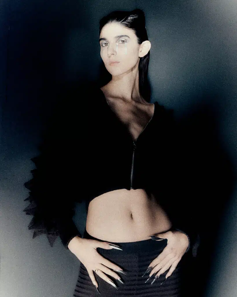 A woman in black jacket holding her stomach.