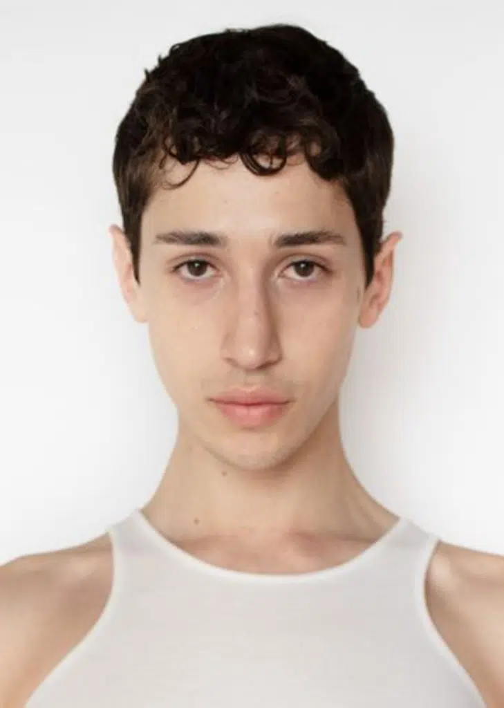 A young man with short hair and a white shirt.