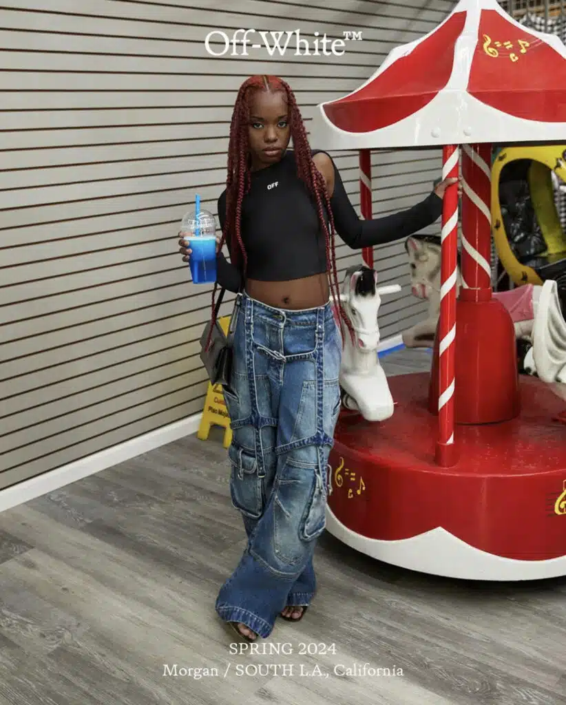 A woman standing next to a carousel with a drink.