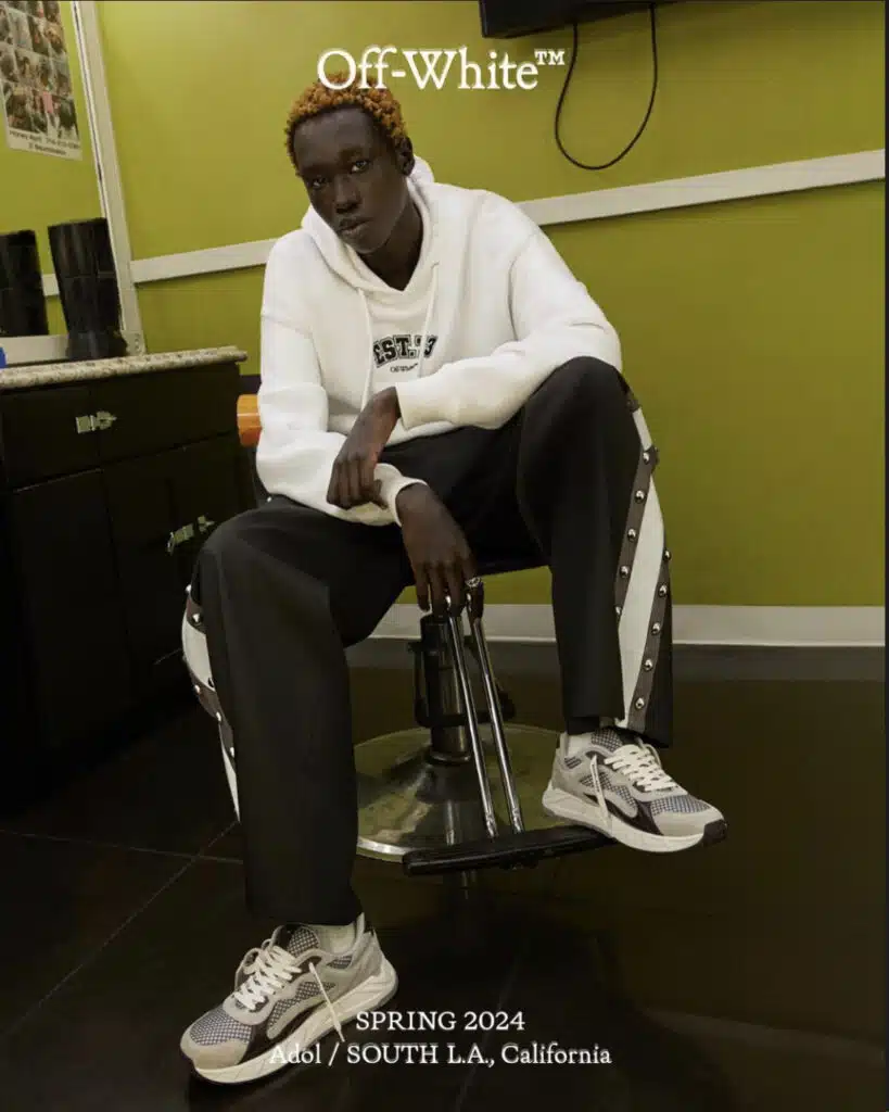 A man sitting on top of a chair in front of a desk.