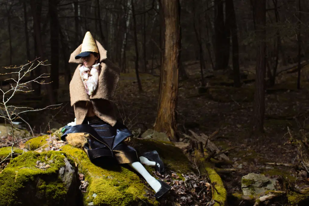 A person sitting on top of a rock in the woods.