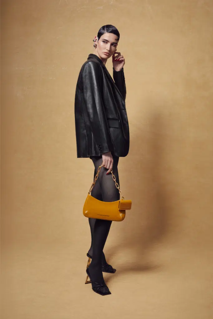 A woman in black jacket holding yellow purse.