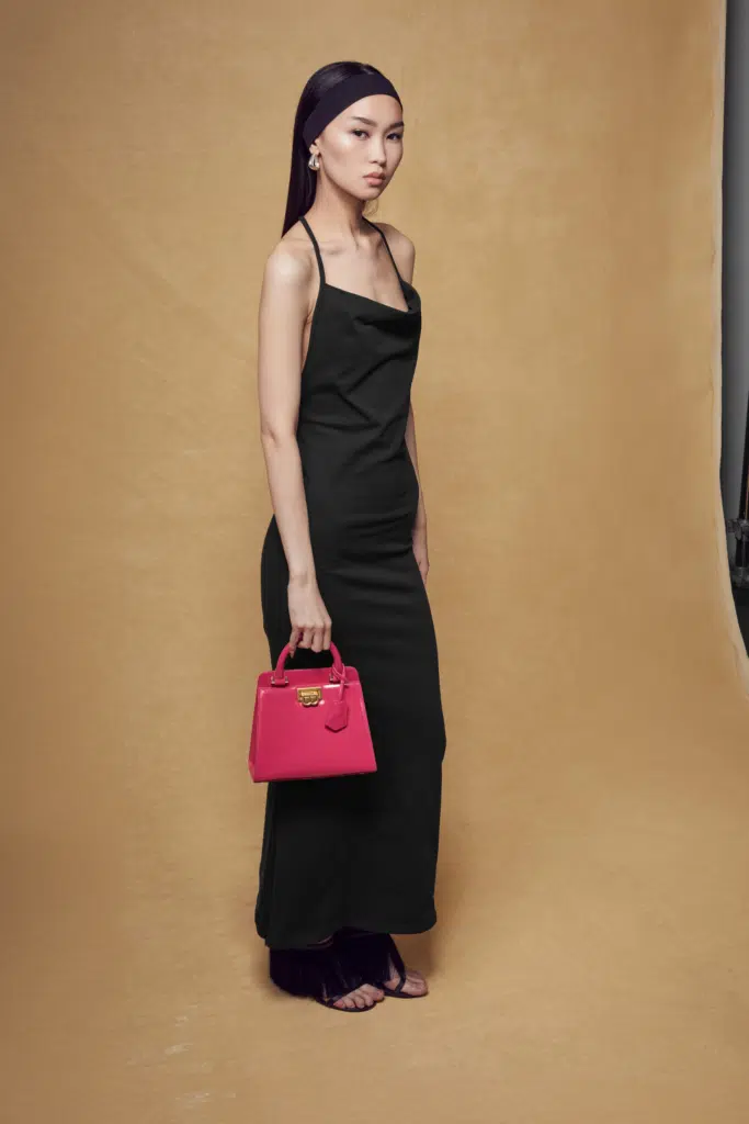 A woman in black dress holding a pink purse.