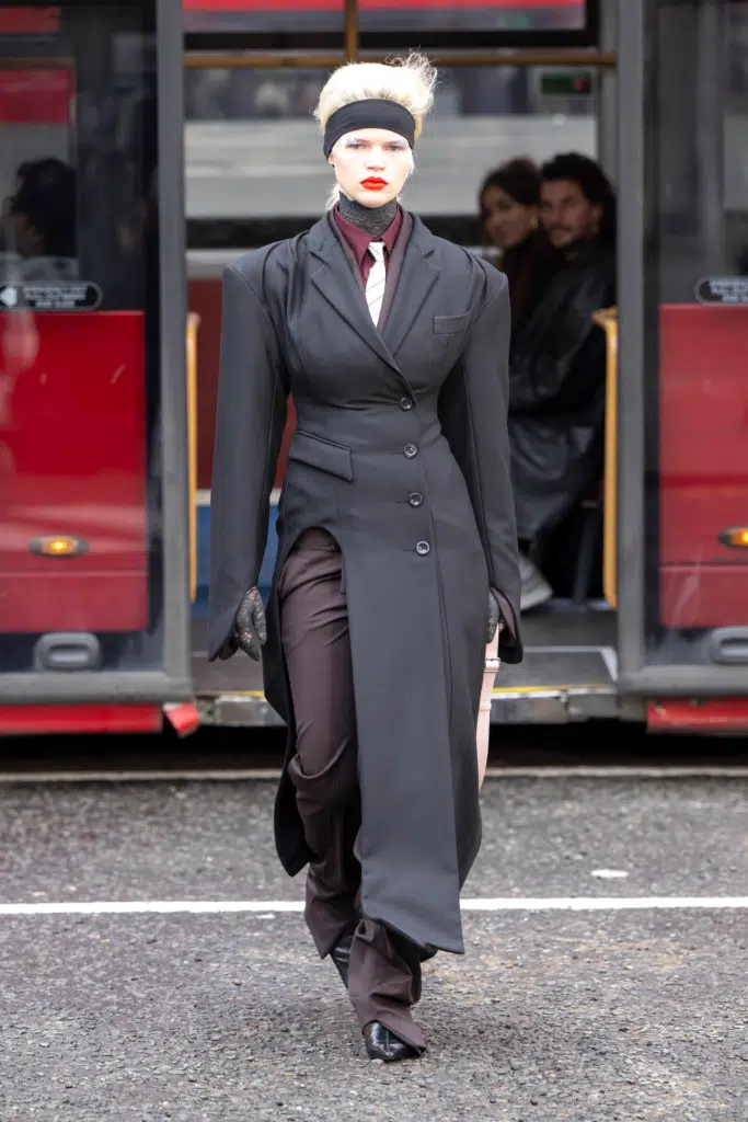 A woman in a long coat and pants walking down the street.