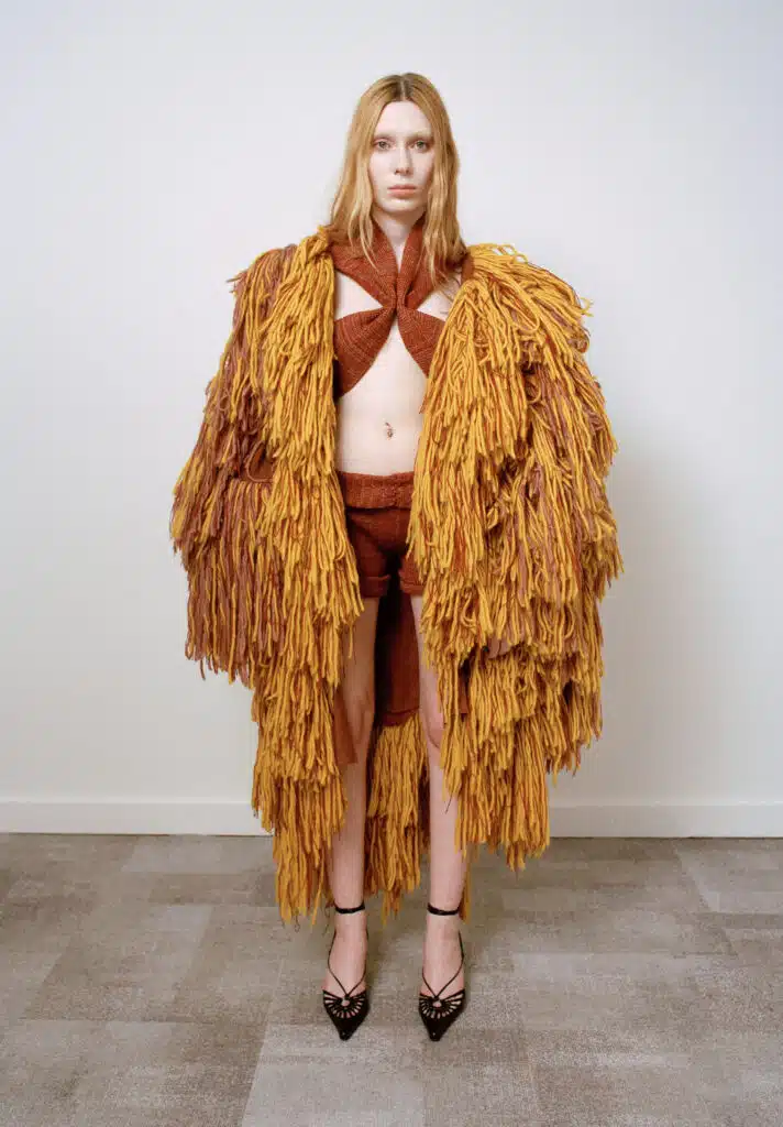 A woman in a yellow coat standing on the floor.