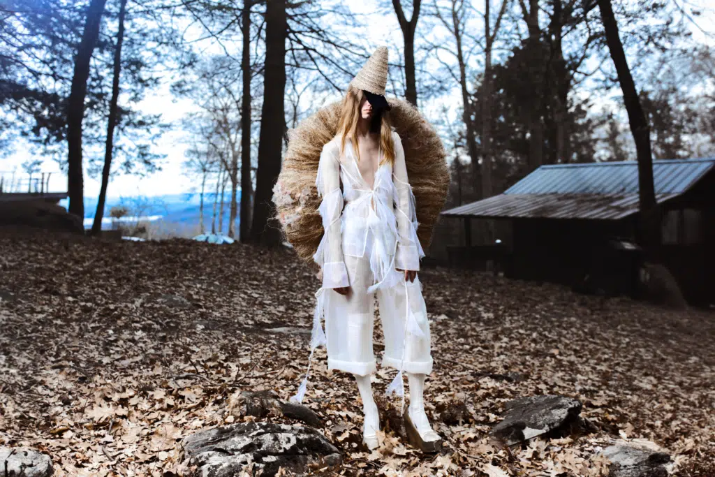 A person in white clothes and fur standing on leaves.