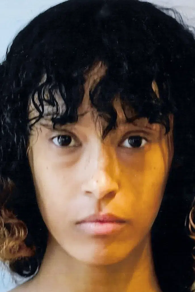 A woman with curly hair and yellow light in her eyes.