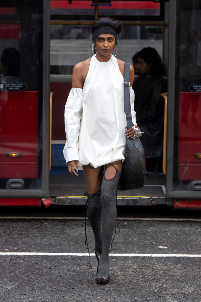 A woman in white dress and stockings walking on the street.