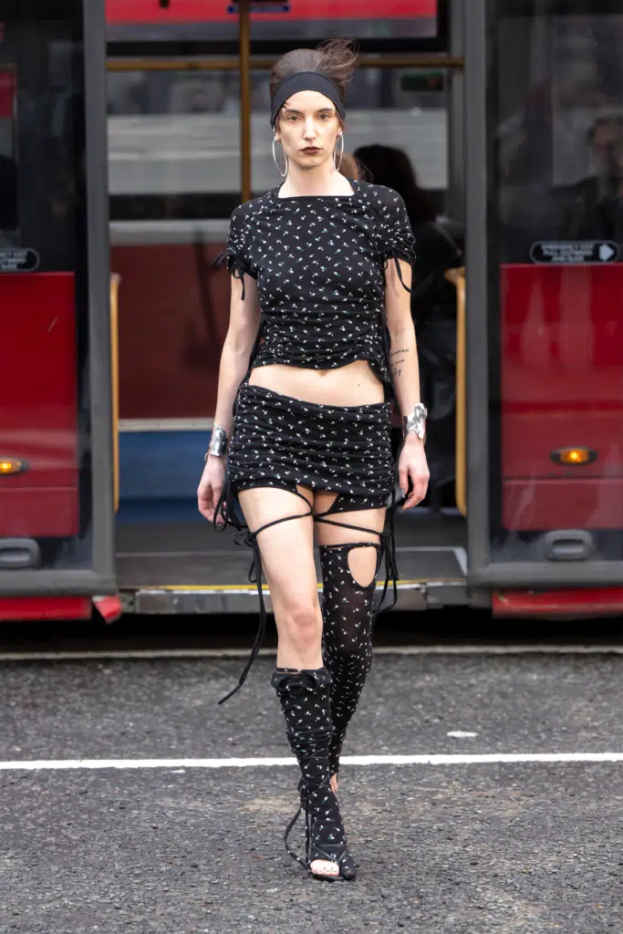 A woman in black dress and boots walking on the street.