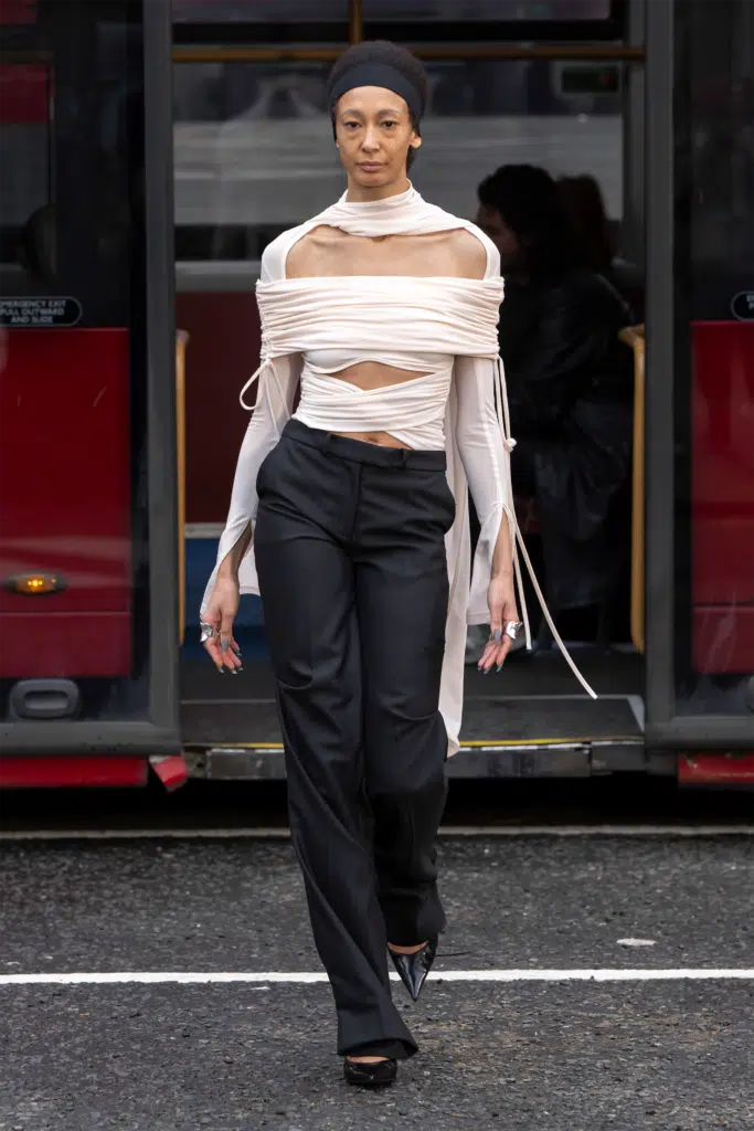 A woman in black pants and white shirt with a long neck.