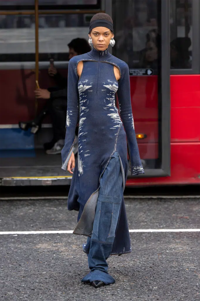 A woman in blue dress standing on the street.