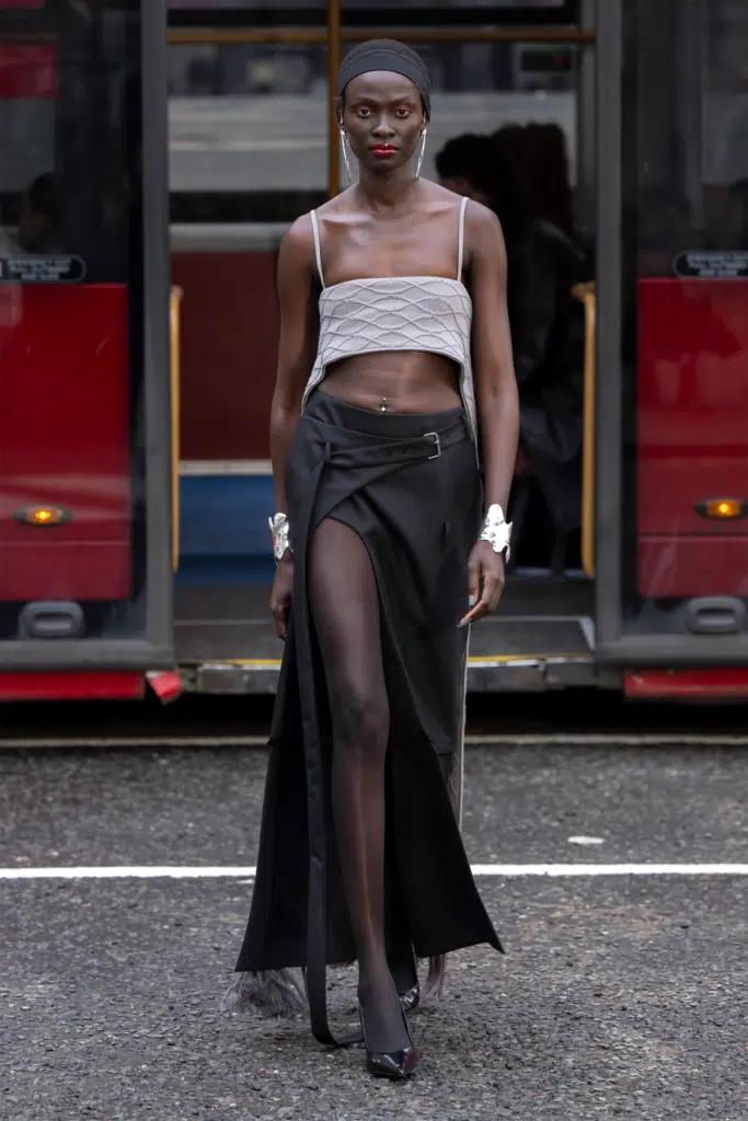 A woman in a long skirt and top standing on the street.