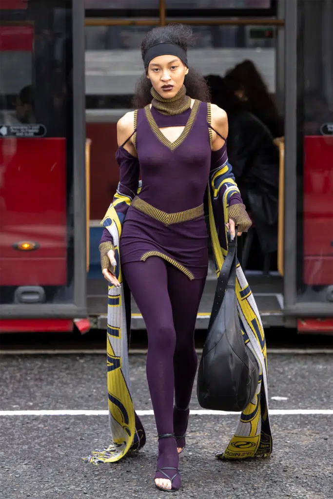 A woman in purple outfit walking on street.