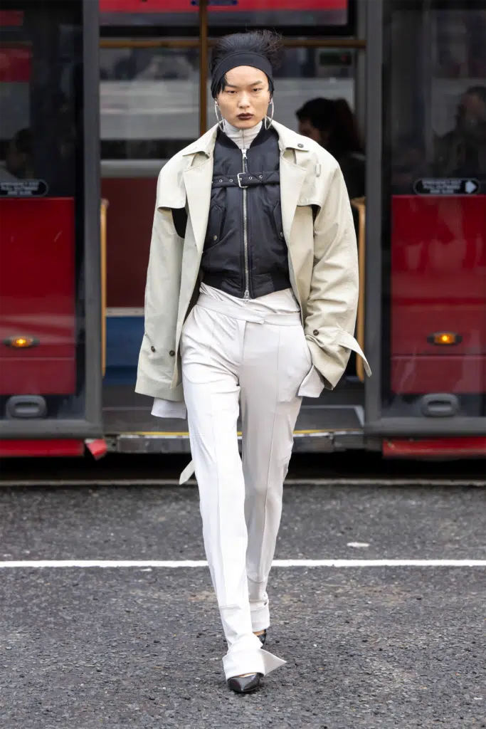 A woman in white pants and jacket walking on the street.