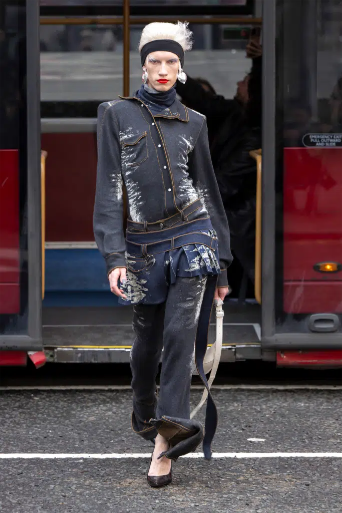 A woman in black jacket and pants standing on sidewalk.