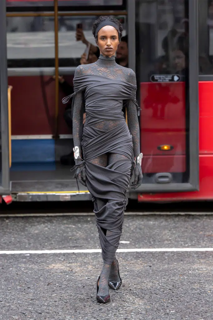 A woman in black dress standing on the street.