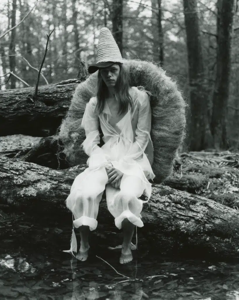 A woman in white sitting on a log.