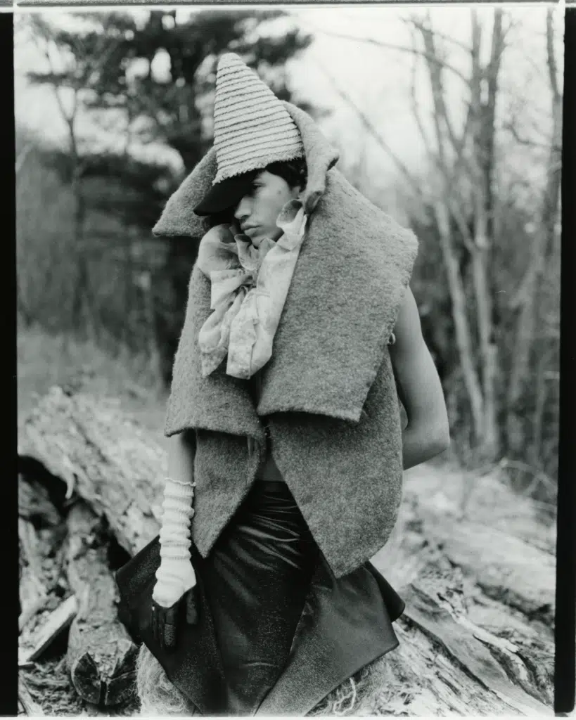 A woman in a hat and coat walking on the side of a road.