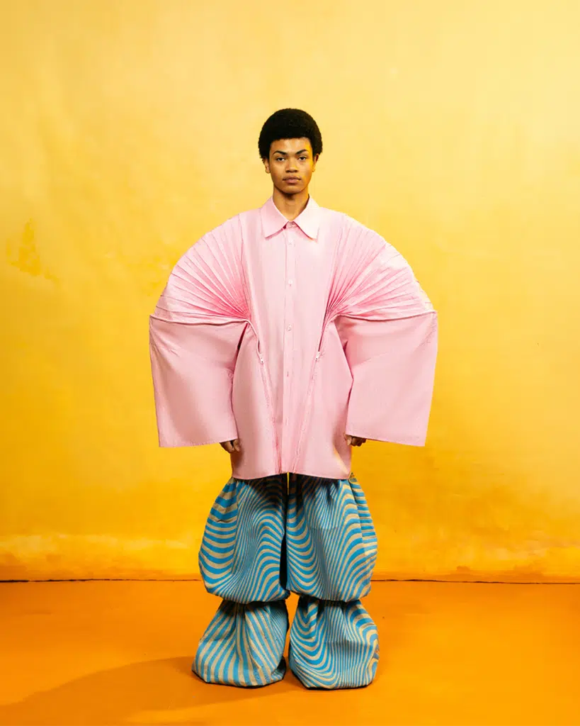 A man in pink shirt and blue pants standing on yellow floor.