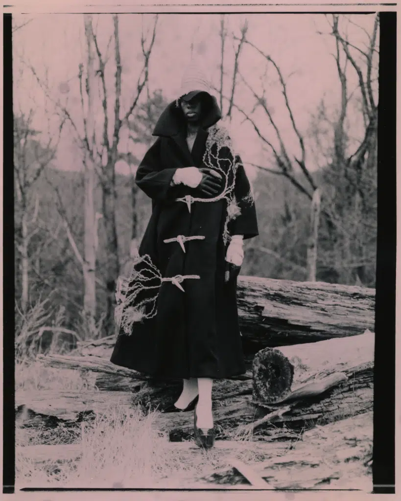 A woman in black coat standing on top of tree.