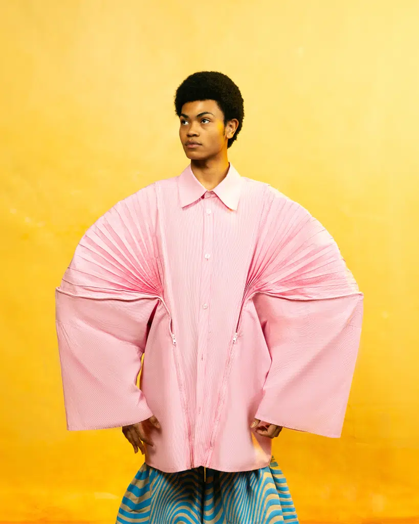 A man in pink shirt with arms folded over his shoulders.