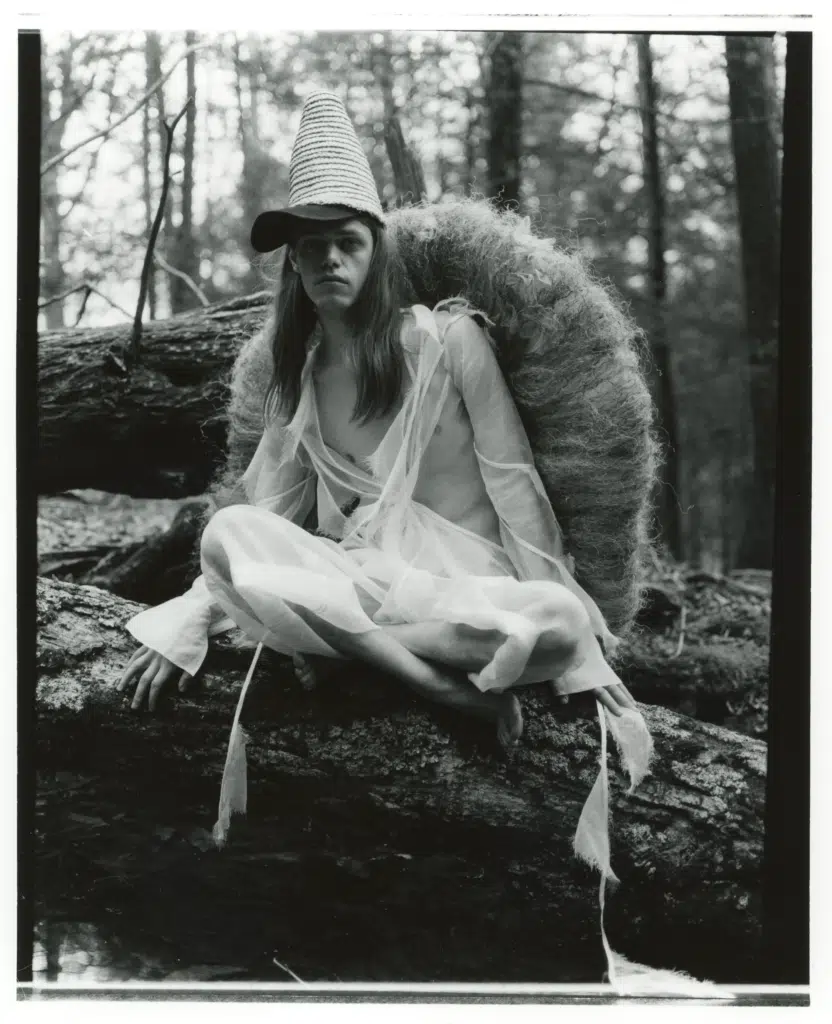 A woman sitting on top of a tree trunk.