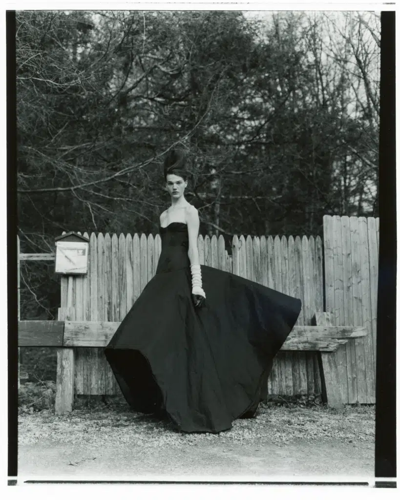 A woman in a black dress standing on top of a bench.