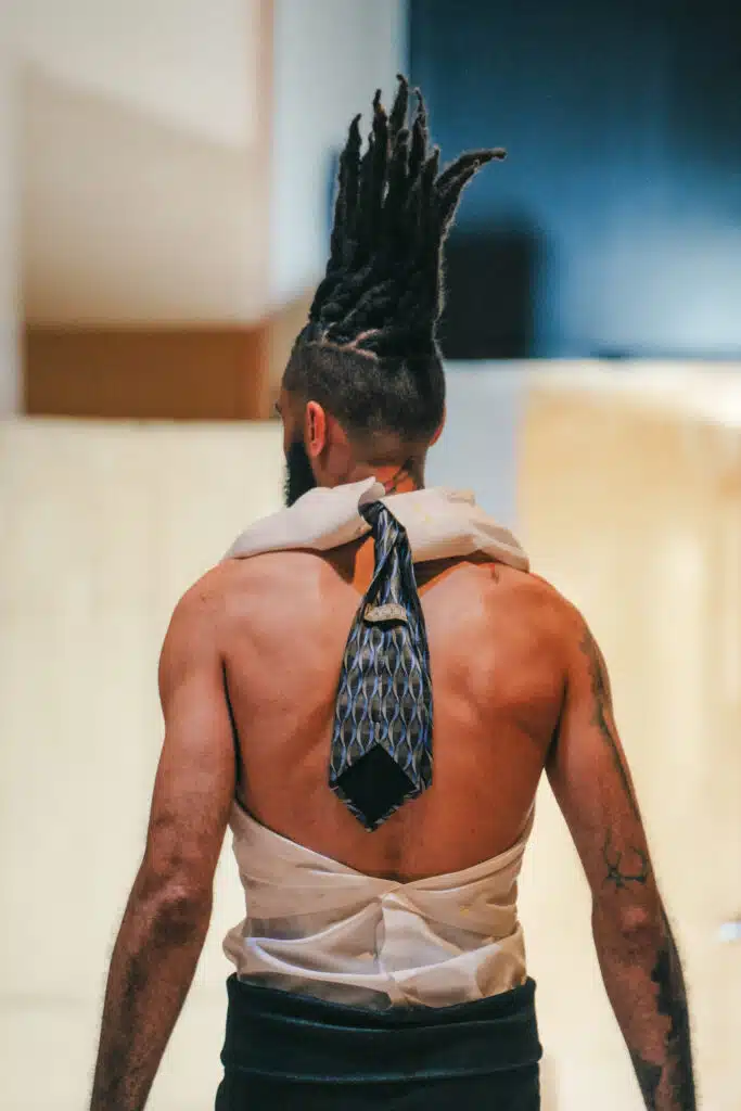 A man with long hair and a tie on his back.