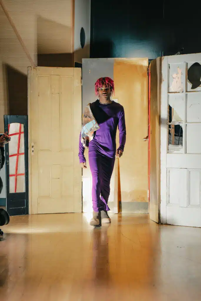 A person in purple and white outfit walking down the hall way.