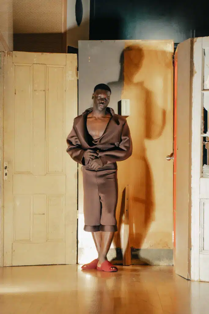 A man in brown robe standing next to door.