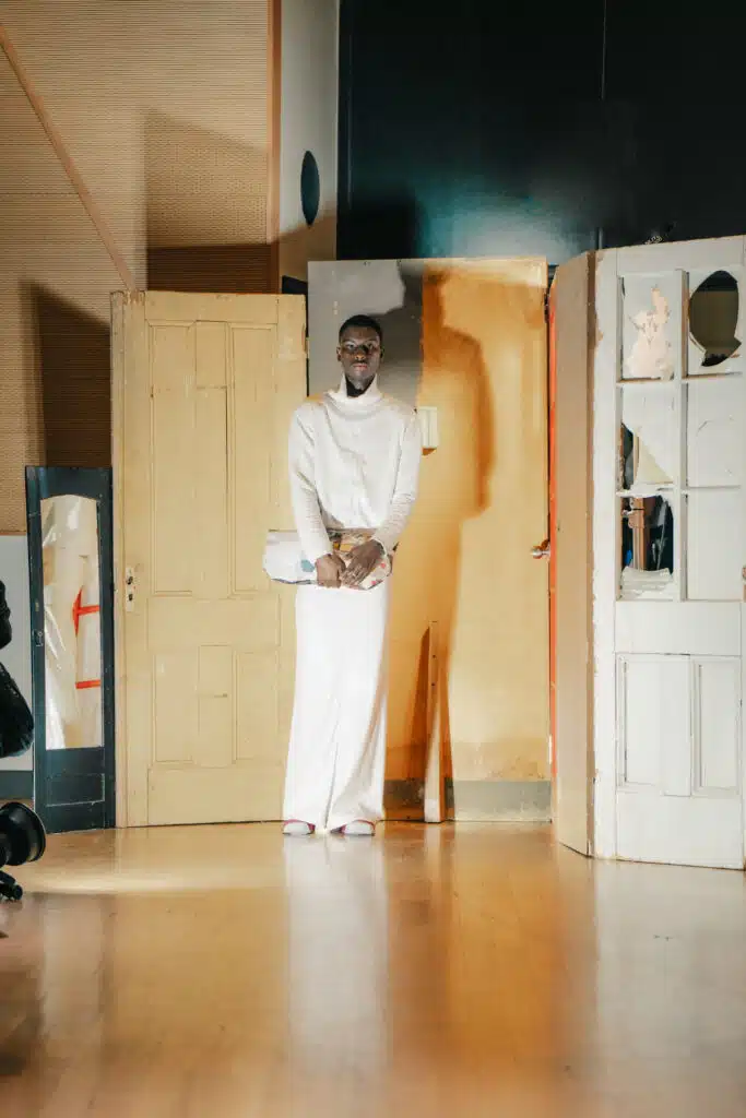 A man in white standing next to a door.