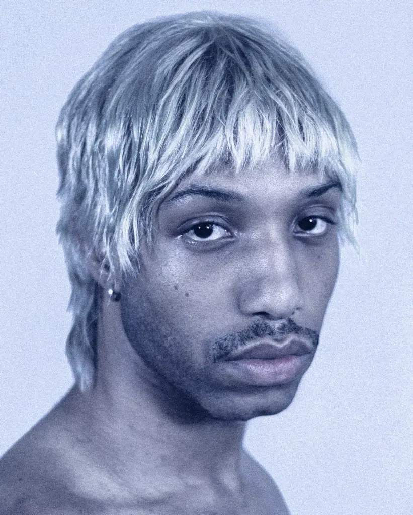 A man with blonde hair and a piercing.