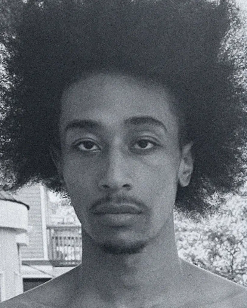 A man with a very large afro is posing for the camera.