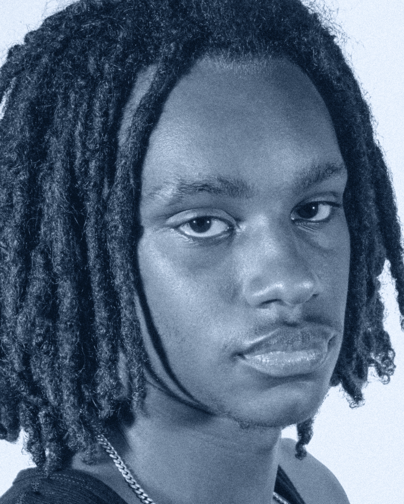 A man with dreadlocks is looking at the camera.