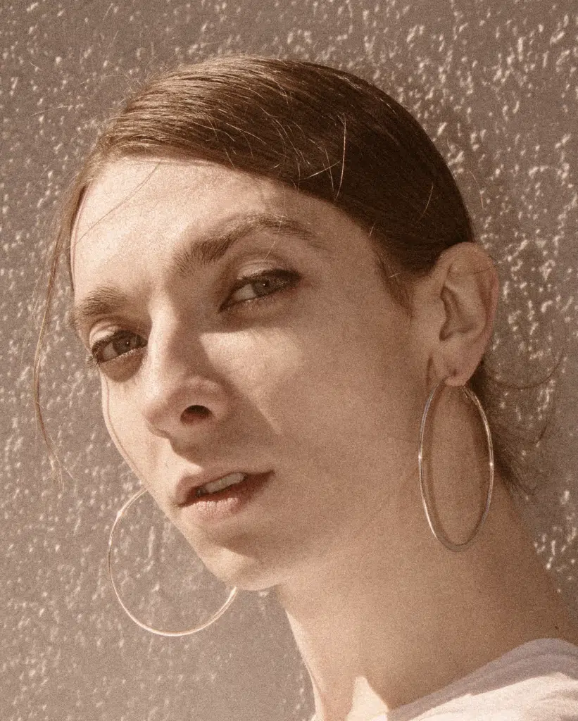 A woman with large earrings is looking at the camera.