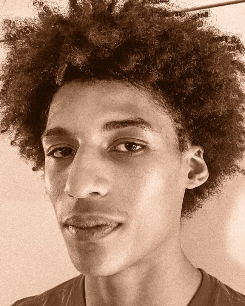 A young man with afro hair posing for the camera.