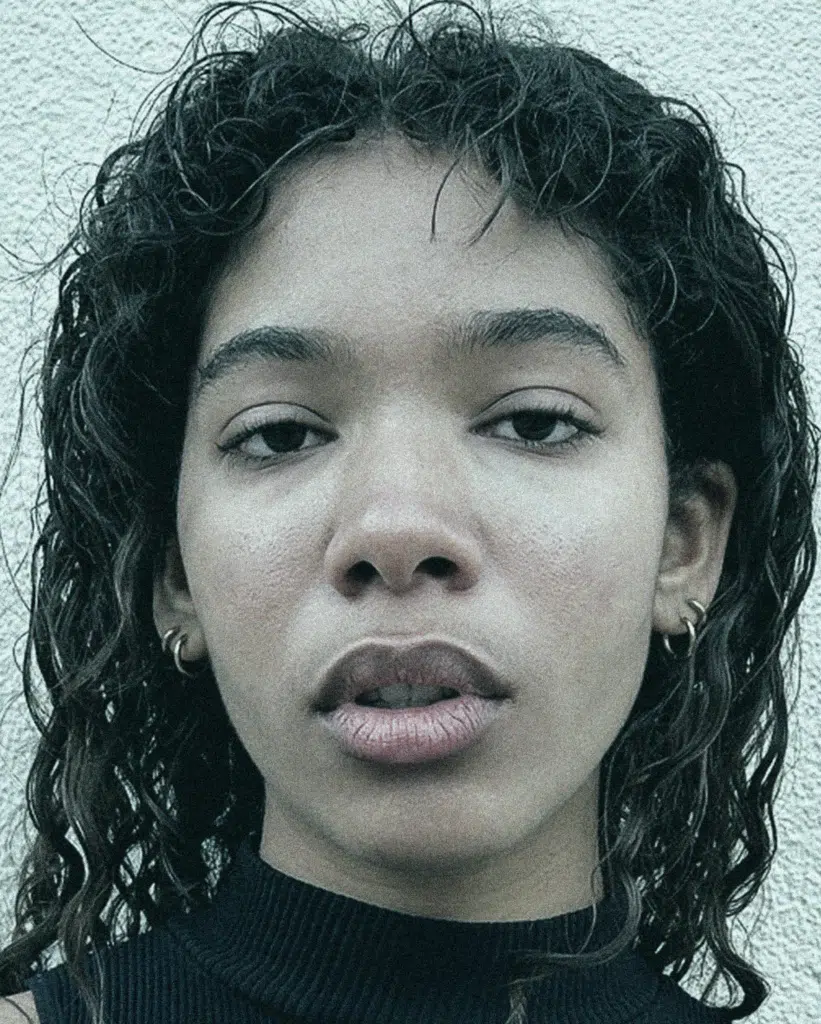 A woman with long hair and piercing wearing black.