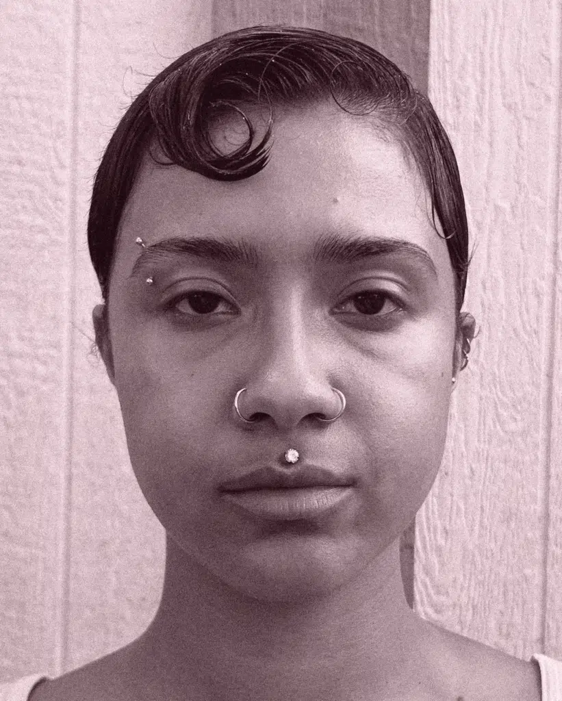 A woman with short hair and a nose ring.