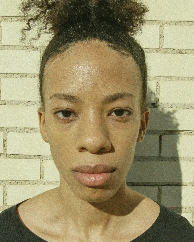 A woman with a black shirt and white brick wall