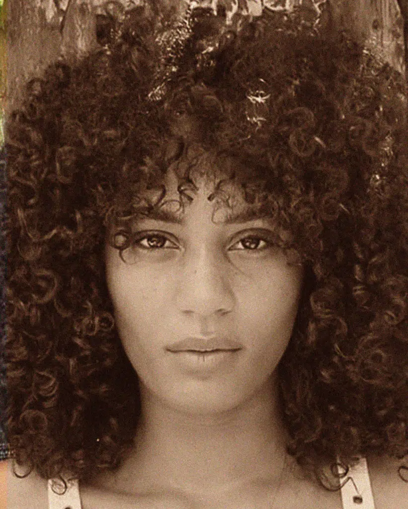 A woman with curly hair is posing for the camera.