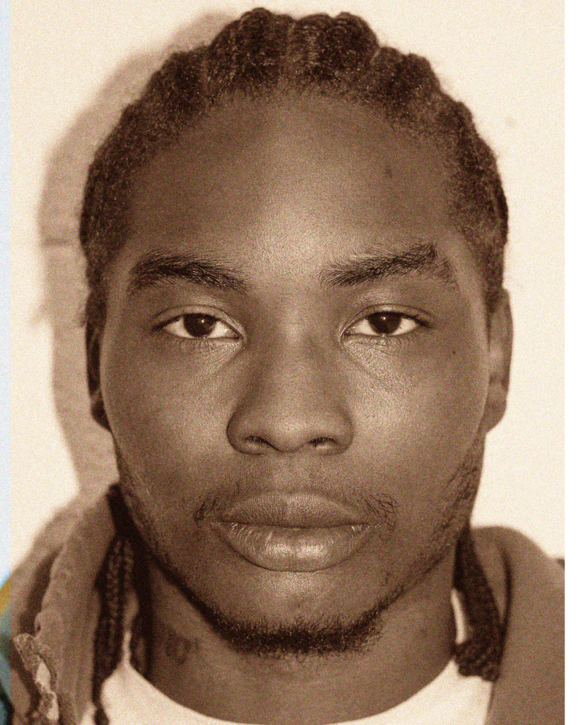 A man with dreadlocks is looking at the camera.