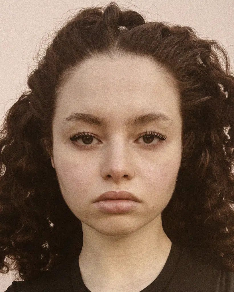 A young woman with curly hair and a black shirt.