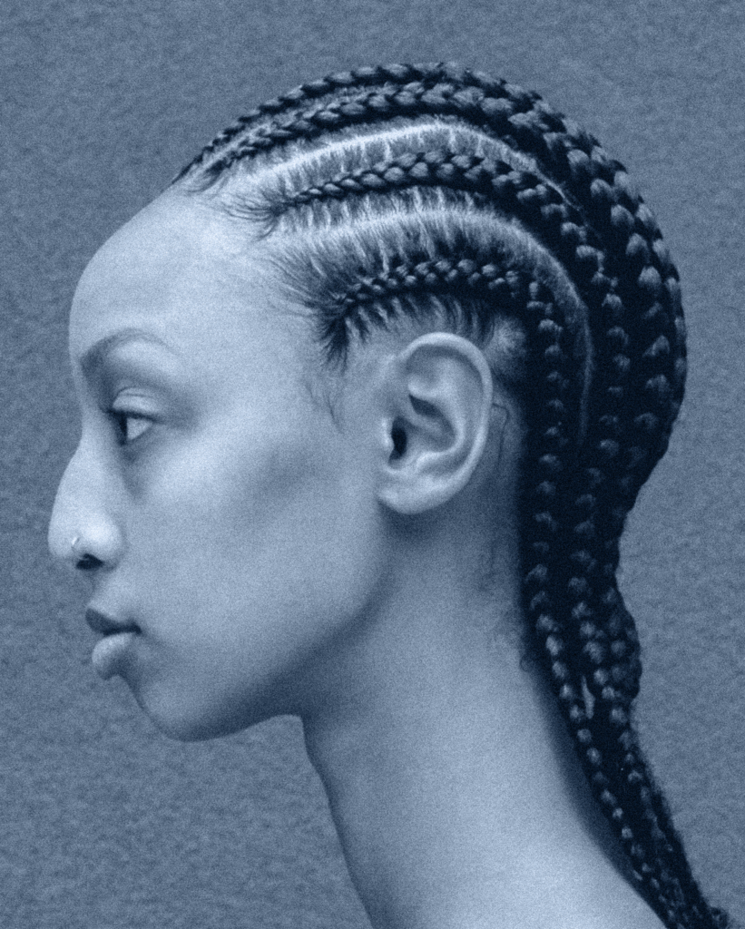 A woman with long braids is looking to her left.