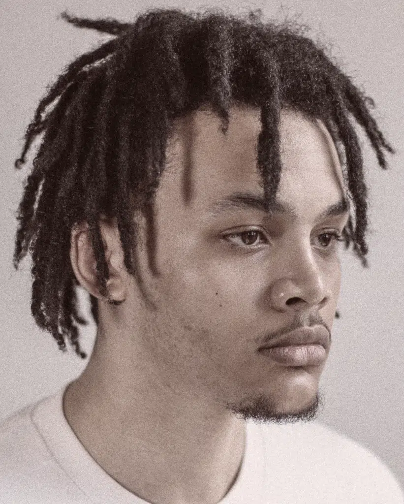 A man with dreadlocks is looking at the camera.