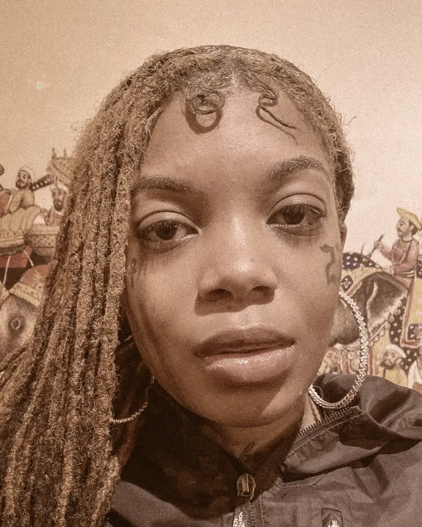 A woman with dreadlocks and tattoos on her head.