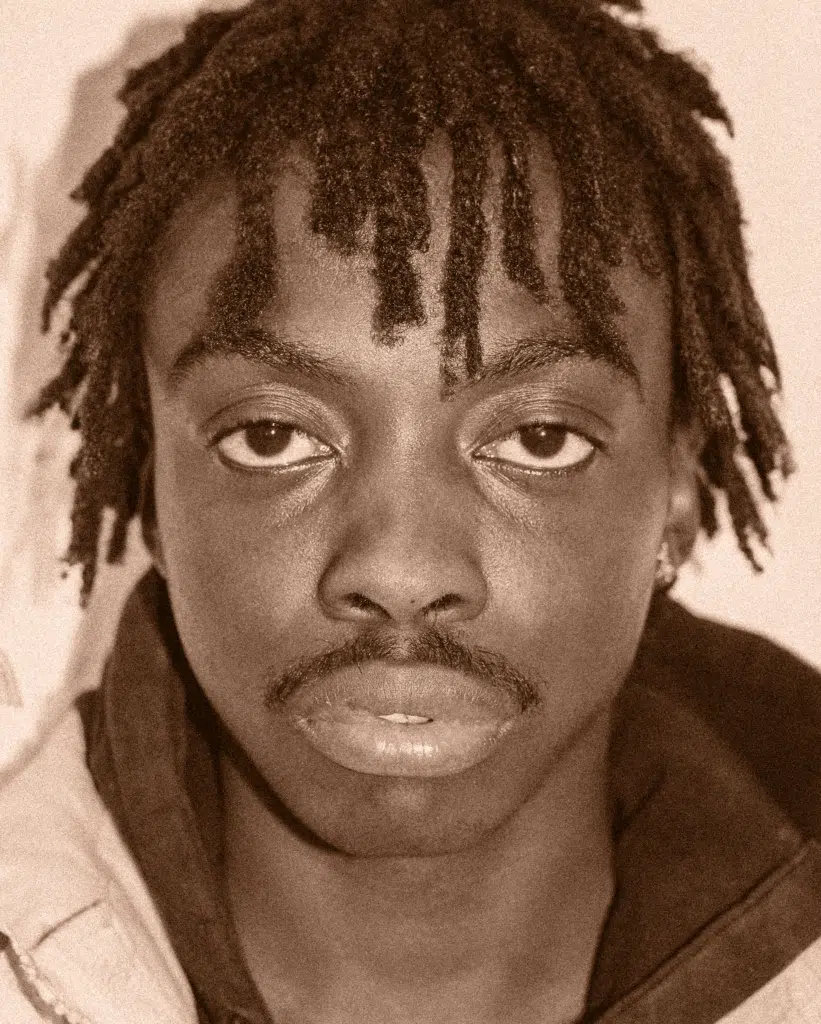 A man with dreadlocks is looking at the camera.